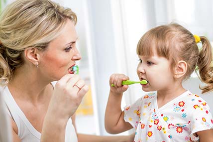 Mutter dient ihrer Tochter als Vorbild beim Zähne putzen.